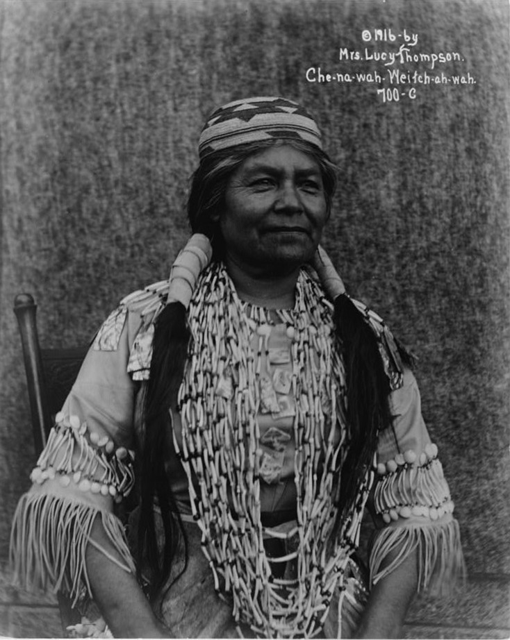 1916 photo of woman with long hair, necklace, wearing a hat